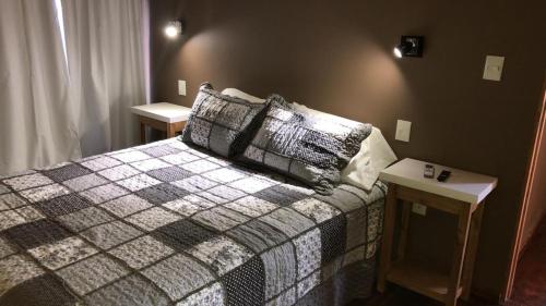1 dormitorio con 1 cama con almohadas y 2 mesas en Duplex Rio Uruguay 161 en Monte Hermoso