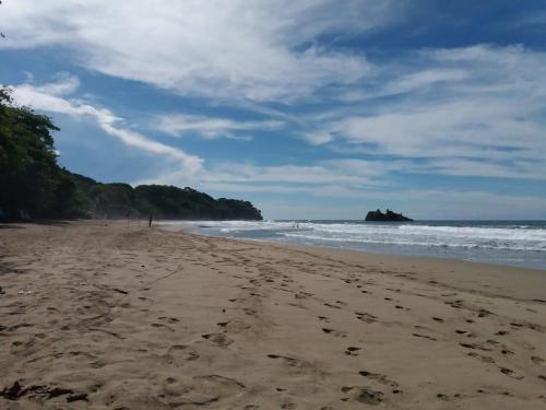 a beach with footprints in the sand and the ocean at Tasty Dayz Hostel in Puerto Viejo