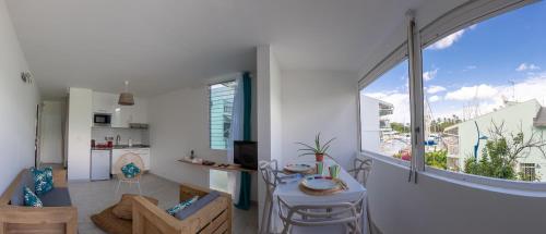 a living room with a table and a large window at Charmant 3 pièces à la marina Pointe du Bout aux 3 ilets in Les Trois-Îlets