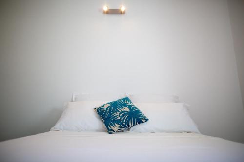 Una cama blanca con una almohada azul. en Beau 3 pièces a la marina des 3 ilets, en Les Trois-Îlets