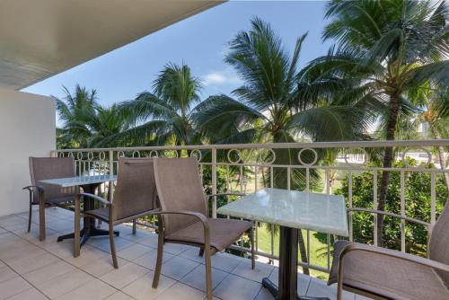 a balcony with chairs and a table and palm trees at Castle Waikiki Shore Beachfront Condominiums in Honolulu