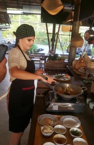 a woman standing in a kitchen preparing food at The Mud - Eco Hotel in Ban Bang Po