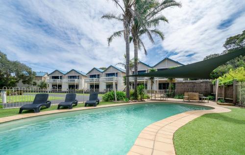 a swimming pool with two chairs and a house at Boathouse Resort Studios and Suites in Blairgowrie