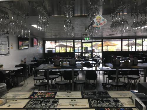 a dining room with tables and chairs and windows at Goondihill Hotel in Innisfail