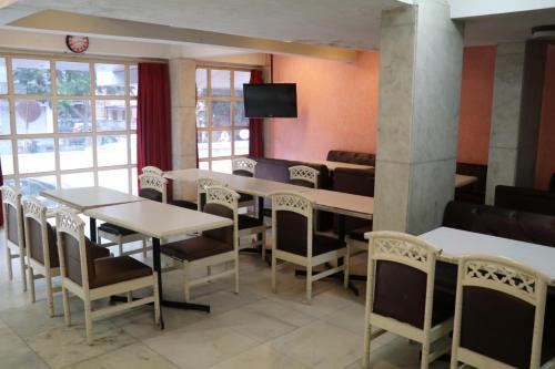 a dining room with tables and chairs and a tv at Hotel Milan International in Mumbai