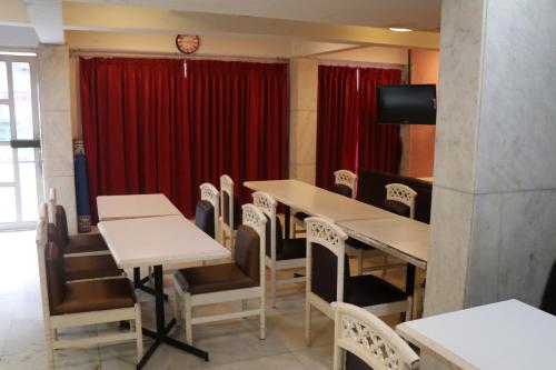 a dining room with tables and chairs and a red curtain at Hotel Milan International in Mumbai