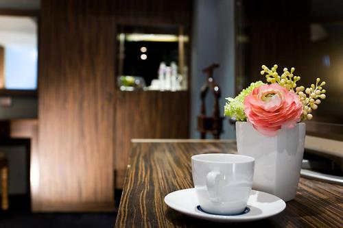 a vase with a flower and a cup on a table at H.M.Hotel in Hsinchu City