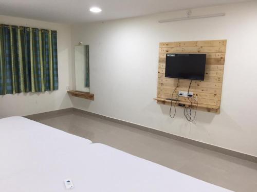 - une chambre avec un lit et une télévision à écran plat dans l'établissement ADITI ROOMS, à Tiruchirappalli