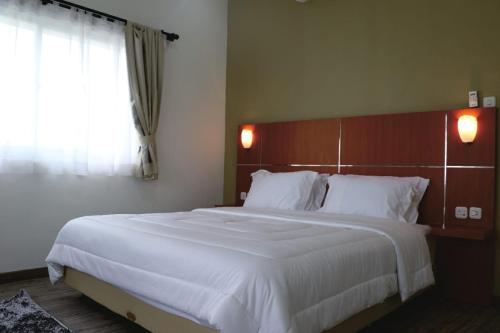 1 dormitorio con 1 cama blanca grande y ventana en Diyar Villas Puncak H1/6, en Puncak