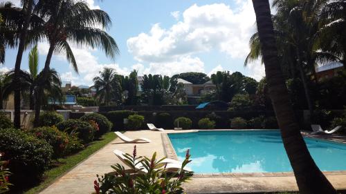 una piscina en un patio con palmeras en Residence Le Palmier, en Flic en Flac