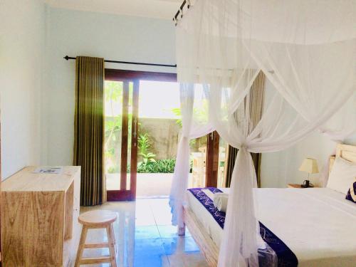 a bedroom with a bed with a white canopy at D'uma Amed Homestay in Amed
