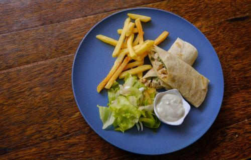 a blue plate with a sandwich and french fries and lettuce at JM Hotel Kuta Lombok in Kuta Lombok