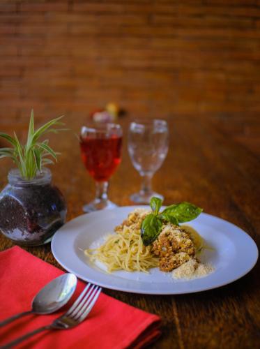 a plate of pasta on a table with two wine glasses at JM Hotel Kuta Lombok in Kuta Lombok
