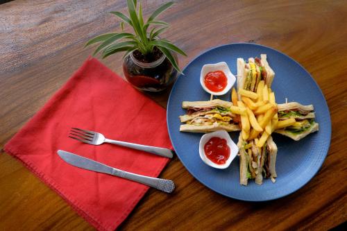 a blue plate of food with a sandwich and french fries at JM Hotel Kuta Lombok in Kuta Lombok