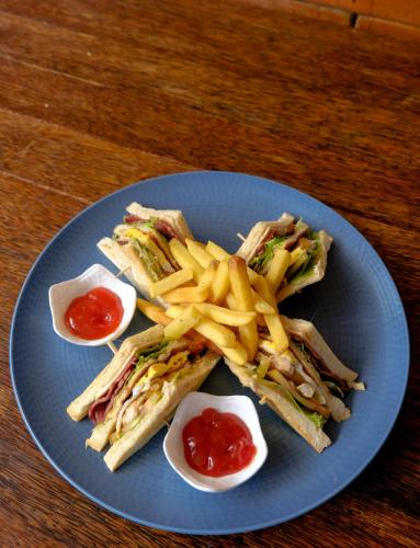 a blue plate with a sandwich and fries and ketchup at JM Hotel Kuta Lombok in Kuta Lombok