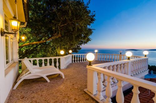a white bench on a balcony looking out at the ocean at Hotel Pansion Villa Antonio in Orebić