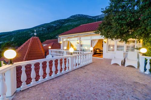 a house with a white fence and mountains in the background at Hotel Pansion Villa Antonio in Orebić