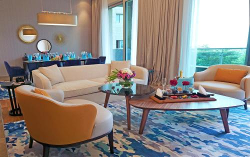 a living room with couches and a table and chairs at Rixos The Palm Hotel & Suites - Ultra All Inclusive in Dubai