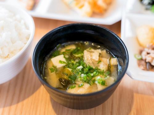 a bowl of soup on a table with plates of food at Super Hotel Takamatsu Kin en kan in Takamatsu