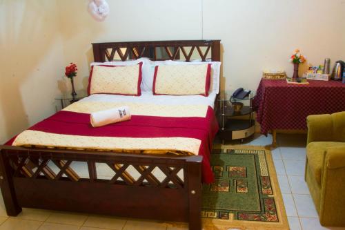 1 dormitorio con 1 cama con almohadas rojas y blancas en Comfort Hotel Entebbe, en Lyamutundwe