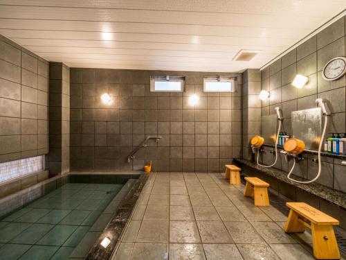 a bathroom with a swimming pool with benches and a sink at Super Hotel Takamatsu Kin en kan in Takamatsu