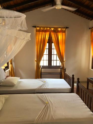 2 camas en un dormitorio con ventana en Villa Araliya, en Negombo