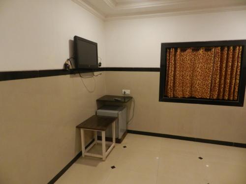 a room with a tv and a desk and a window at Sayeban Hotel in Matheran