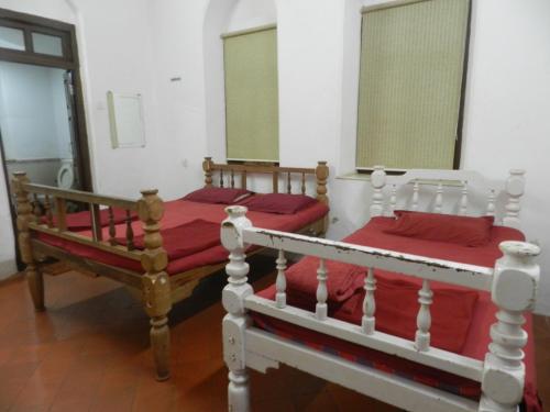 two beds in a room with red sheets at Sayeban Hotel in Matheran