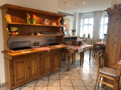una cocina con armarios de madera, mesas y sillas en Hotel Alter Giebel, en Bottrop-Kirchhellen