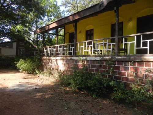 a brick retaining wall next to a yellow building at Sayeban Hotel in Matheran