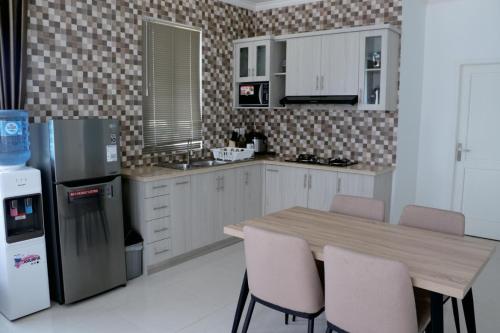 a kitchen with a table with chairs and a refrigerator at Diyar Villas Puncak F4/8 in Puncak