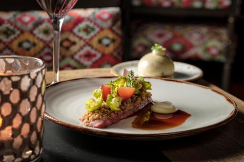 a plate of food on a table next to a glass at Valsana Hotel Arosa - Small Luxury Hotel in Arosa