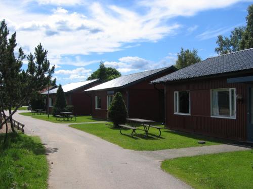 a row of cottages with benches in the grass at Ätrans Stugby & Fritidsanläggning in Ätran