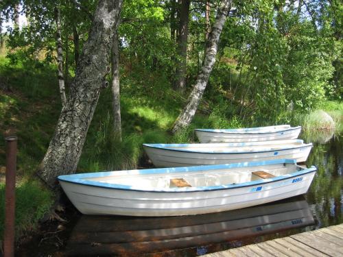 three boats sitting in the water next to trees at Ätrans Stugby & Fritidsanläggning in Ätran