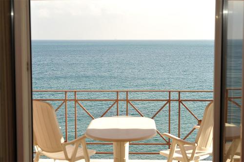 two chairs and a table on a balcony overlooking the ocean at Hotel Pelagos Studios in Platána