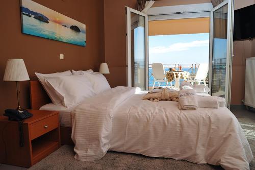 a bedroom with a white bed and a balcony at Hotel Pelagos Studios in Platána