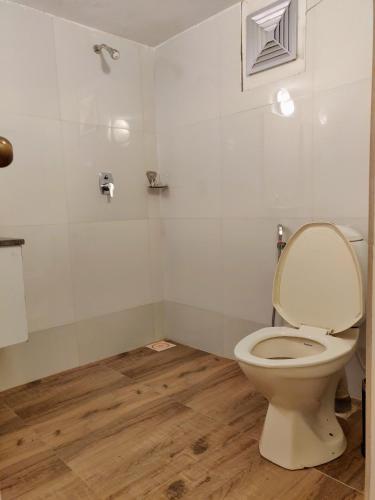 a bathroom with a toilet with the lid up at Bedrock Boutique Hostel in Baga
