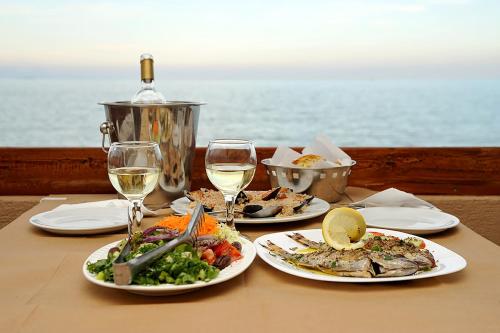 a table with two plates of food and two glasses of wine at Hotel Pelagos Studios in Platána