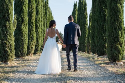 a bride and groom walking through a row of trees at Villa S.Andrea in San Casciano in Val di Pesa
