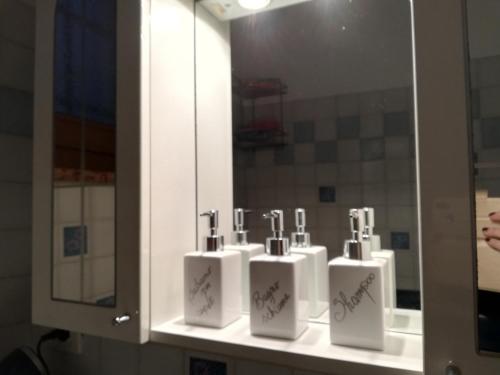 a bathroom with three soap dispensers in front of a mirror at Casetta next to the Creek Dino Buzzati in Belluno