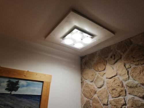 a ceiling light in a room with a stone wall at Casetta next to the Creek Dino Buzzati in Belluno
