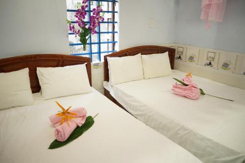2 letti in una camera con fiori rosa di Bai Huong homestay a Hoi An