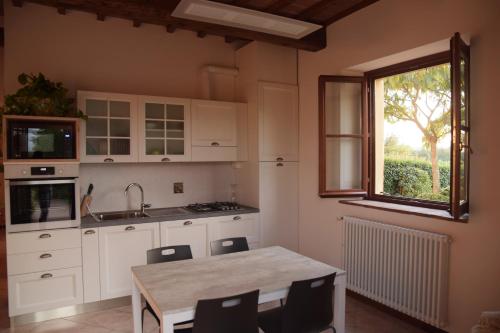 cocina con armarios blancos, mesa y ventana en Mugello Tuscany Bosso di Sopra, en Borgo San Lorenzo