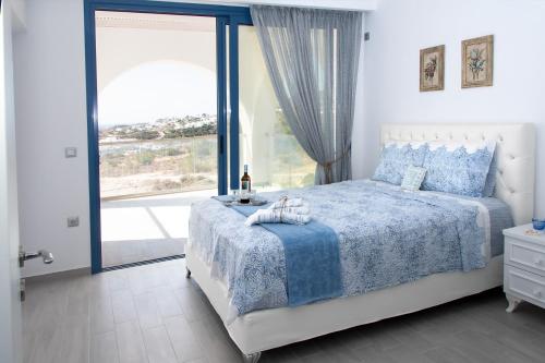 Aelia Luxury Villa في أموبي: غرفة نوم بسرير ونافذة كبيرة
