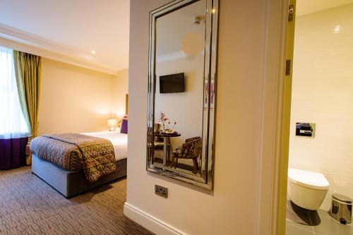 トラリーにあるGrand Hotel Traleeのベッドと鏡が備わるホテルルーム