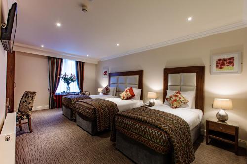 a hotel room with two beds and two chairs at Grand Hotel Tralee in Tralee