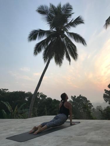 a woman sitting on a mat in front of a palm tree at Tabula Rasa Resort & Spa in Galle