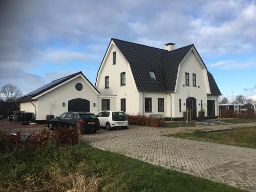 a white house with two cars parked in a driveway at Slaapplaatsen 2-4 personen voor bezoek DTRH in Beuningen