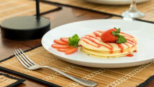 a plate of pancakes and strawberries on a table at Deltora Villa - free drop off to Galle Fort by TukTuk in Galle