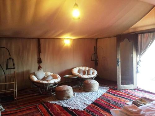 a room with two chairs and a table in a tent at Boutchrafine Luxury Camp in Erfoud